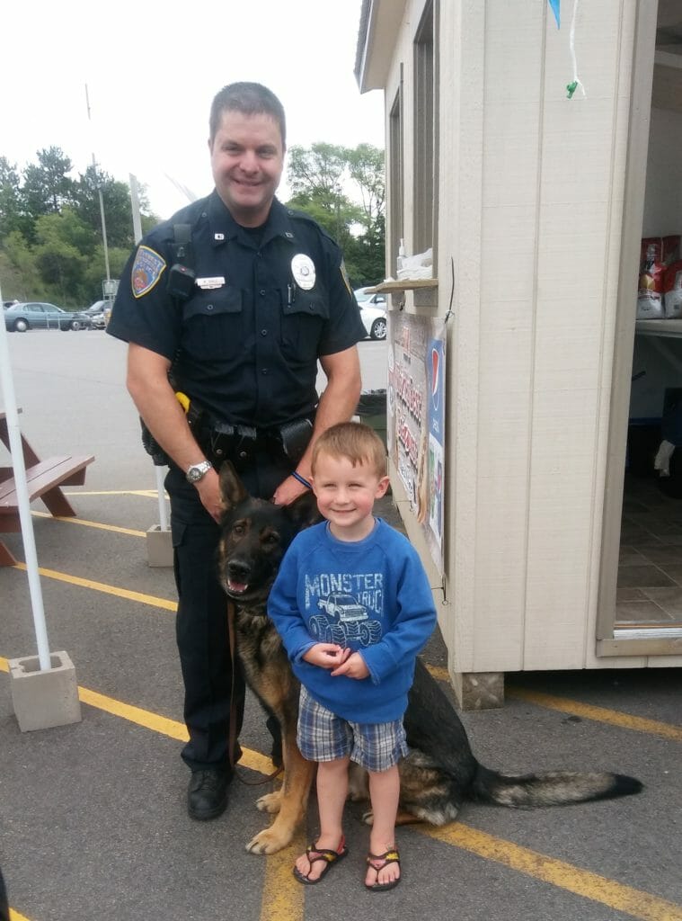 Police Officer and service dog posing with child