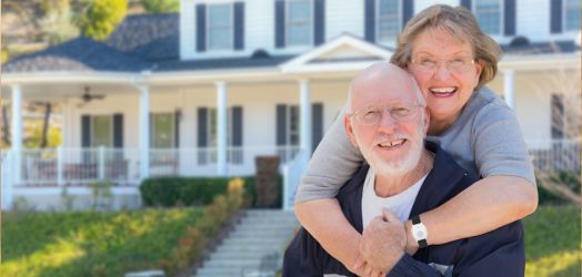 Older couple in front of their house with a medical alert